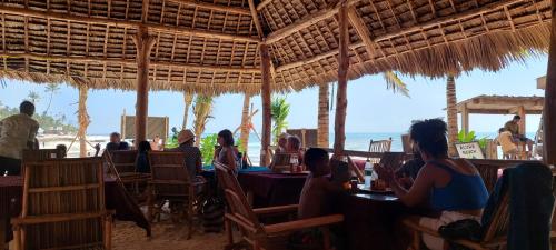 a group of people sitting at a restaurant on the beach at Aquarium Beach House in Nungwi