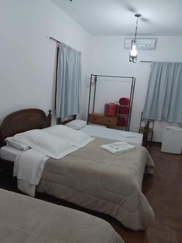 a bedroom with a bed with white sheets and a mirror at POUSADA PARLATORIUM in Tiradentes