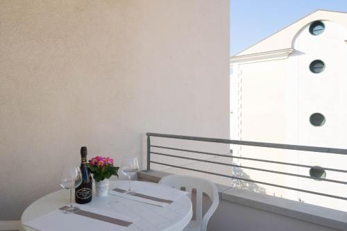 - une table blanche avec des bouteilles de vin et des fleurs sur le balcon dans l'établissement Villa Jadì Sottomarina, à Chioggia