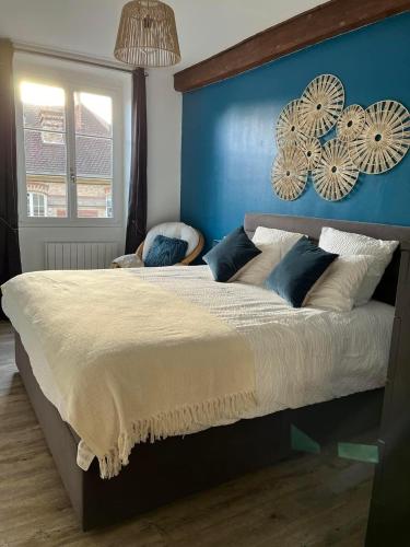 a bedroom with a large bed with a blue wall at Le relais d'Eugènie en hyper centre-ville in Compiègne