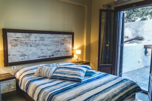 a bedroom with a bed and a large window at Theoxenia Kasos Luxury Apartments in Panayía