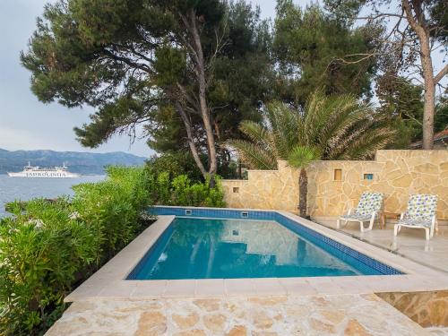 a swimming pool with two chairs next to the water at Villas Violet & Rosemary in Supetar