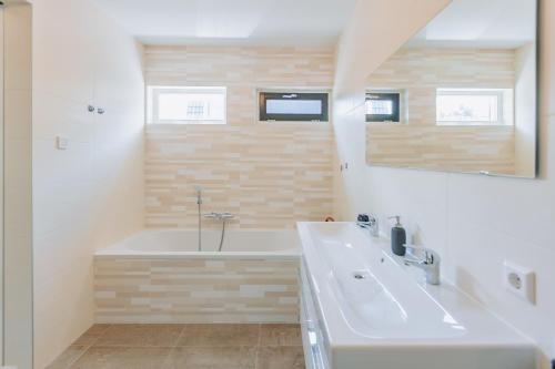 a bathroom with a tub and a sink and a mirror at Brand new bright luxurious villa in Amsterdam! in Amsterdam