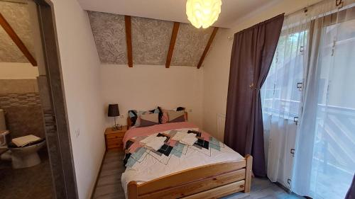 um pequeno quarto com uma cama e uma janela em Vis Împlinit em Cartisoara