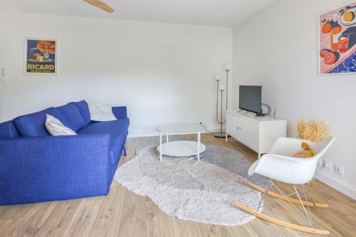 sala de estar con sofá azul, mesa y sillas en Appartement Médalie - Welkeys, en Toulon