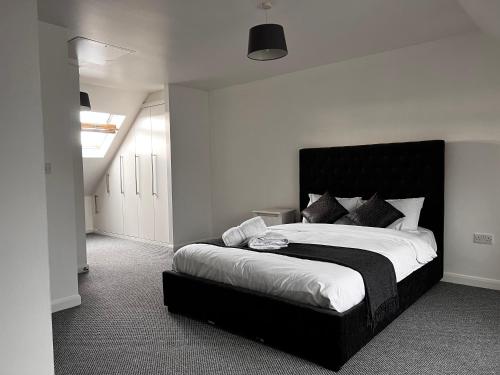 a bedroom with a large bed with a black headboard at VRLProperties. in Gloucester