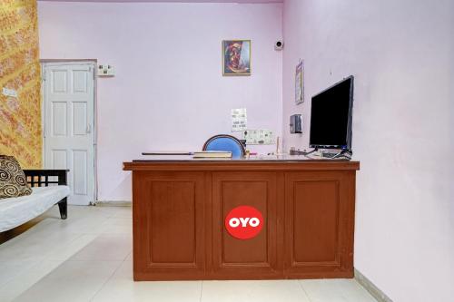 OYO Flagship Raj Hotel Near Juhu Beach في مومباي: مكتب يوجد تلفزيون فوقه في غرفة