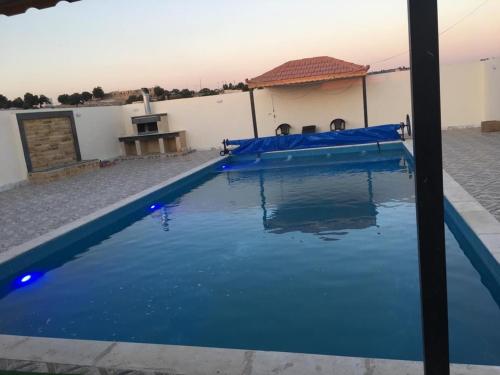 una piscina azul frente a un edificio en Poolside Perfection - Private Pool & BBQ, en Irbid