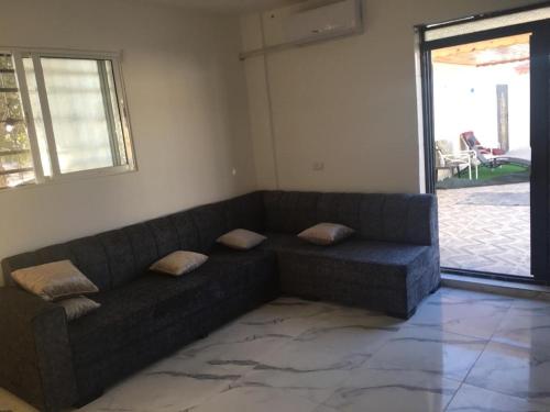 a couch sitting in a living room with a window at Poolside Perfection - Private Pool & BBQ in Irbid