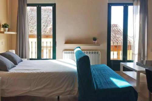 a bedroom with a bed and a desk and windows at Estudio en Centro de Segovia 2 in Segovia