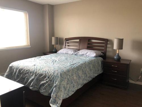 a bedroom with a bed and two lamps on night stands at Signature Suites By Oasis Corporate Rentals in Grande Prairie