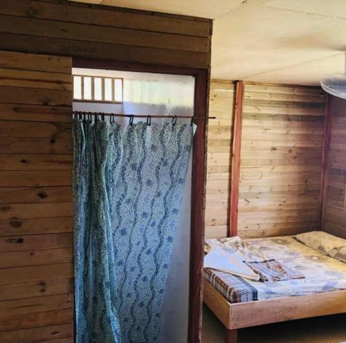 Bett in einem Holzzimmer mit Vorhang in der Unterkunft HOSTAL CRUZ DEL MAR in Capurganá
