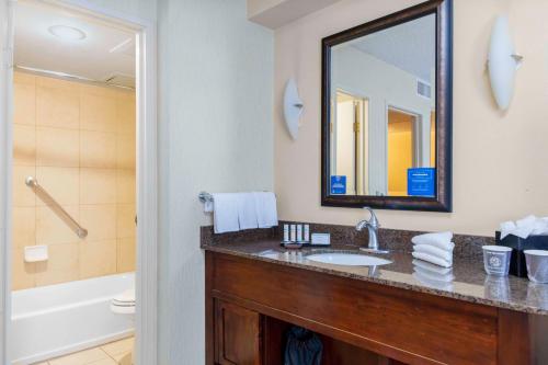 a bathroom with a sink and a mirror and a tub at Embassy Suites by Hilton Kansas City Plaza in Kansas City
