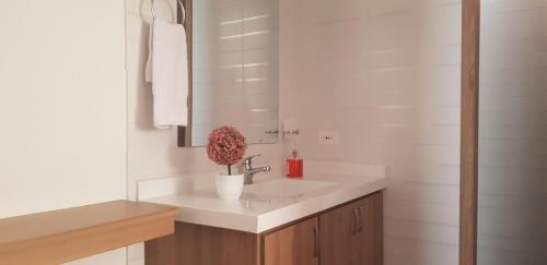Baño blanco con lavabo y espejo en Aptahotel Guest House en San Gil