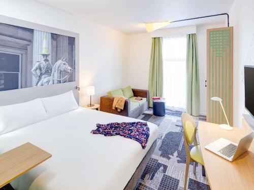 um quarto com uma cama e uma secretária com um computador portátil em ibis Styles Glasgow Centre George Square em Glasgow