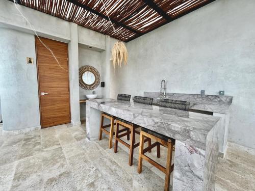 a kitchen with a large marble counter with stools at Beautiful Rooftop Apartment with Private Terrace, Infinity Pool with Aerial Views, Jacuzzi-Sauna-Gym-Cinema-Coworking in Tulum