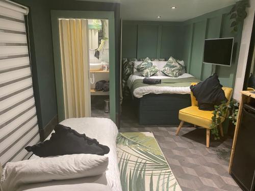 a small room with two beds and a yellow chair at Mini Love Island style guest house with a hot private swimming pool and heated dining pod, secretly located in the busy suburbs of Nottingham in Nottingham