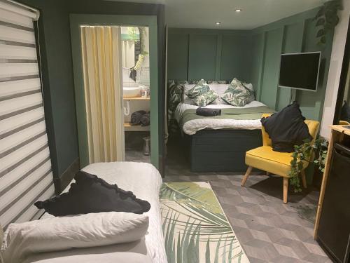 a small room with two beds and a yellow chair at Mini Love Island style guest house includes personal warm 24 hour swimming pool, outdoor bathtub, BBQ and fire pit, all this is secretly located in the busy suburbs of Nottingham in Nottingham