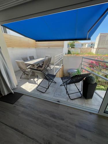 d'une terrasse avec une table, des chaises et un parasol bleu. dans l'établissement Idéal famille, maison neuve climatisée à 7 mn à pieds plage Minimes, à La Rochelle