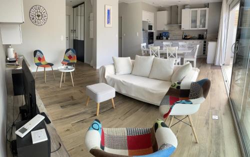 un salon avec un canapé et des chaises et une cuisine dans l'établissement Idéal famille, maison neuve climatisée à 7 mn à pieds plage Minimes, à La Rochelle
