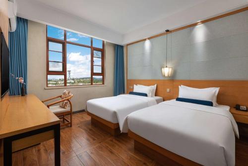 Habitación de hotel con 2 camas, escritorio y ventana en Days Inn by Wyndham Dali Erhai Park, en Dali