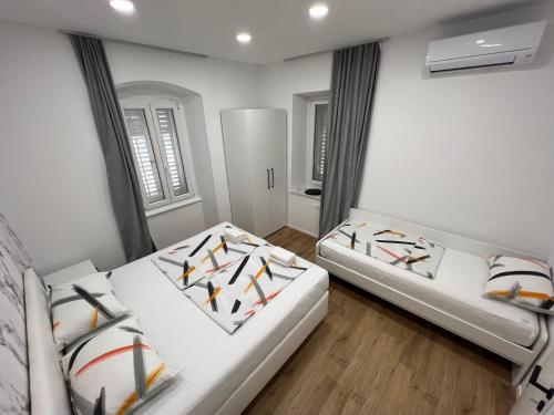 two beds in a room with white walls and wooden floors at Grand Apartment Piran in Piran
