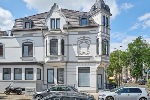 a white building with a clock tower on a street at Charmante Altbremer Wohnung I Wintergarten I Küche I Balkon in Bremen