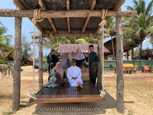 a group of people sitting on a wooden swing at Bayu Beach Penarek in Penarek