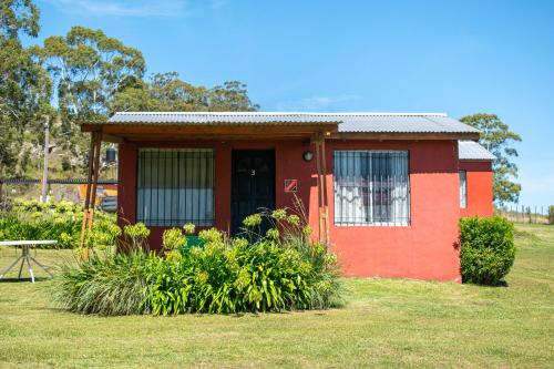 una pequeña casa roja con una mesa en un patio en Cabañas Los Pioneros en Tandil