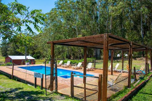 a swimming pool with a wooden pavilion next to a swimming pool at Cabañas Los Pioneros in Tandil