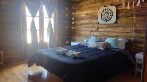 um quarto com uma cama grande num quarto com paredes de madeira em cabañas de montaña em Uspallata