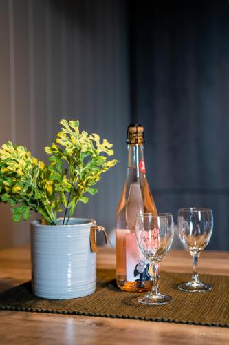 a bottle of beer and two wine glasses on a table at Alpan Apartments, Lyngenfjord in Olderdalen