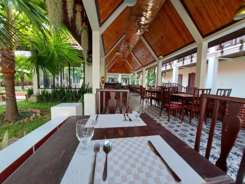 uma sala de jantar com mesas, cadeiras e árvores em Sunrise Garden House - Luang Prabang em Luang Prabang