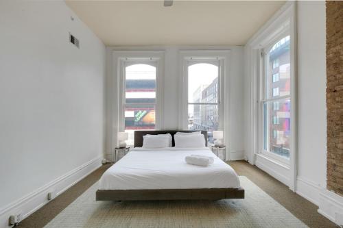 a white bedroom with a bed and two windows at Historic Charm, Walkable Entertainment in Louisville