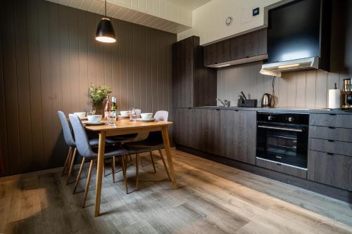 a kitchen with a wooden table and chairs in a kitchen at Alpan Apartments, Lyngenfjord in Olderdalen