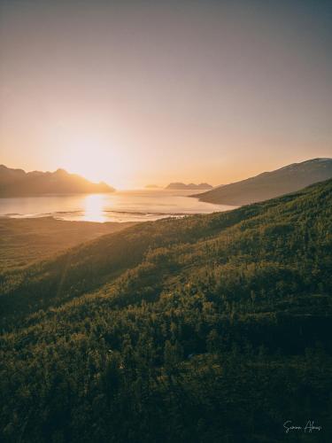 an aerial view of a lake with the sun setting on the horizon at Alpan Apartments, Lyngenfjord in Olderdalen