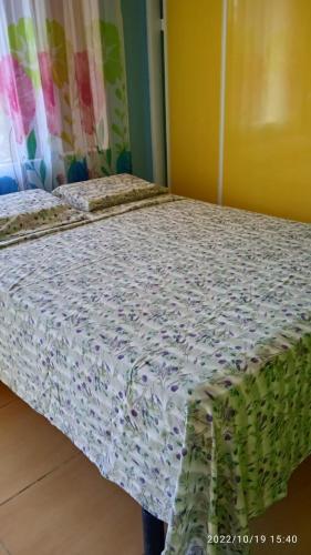 a bedroom with a bed with a floral bedspread at Entre Mer et Montagne in Goyave
