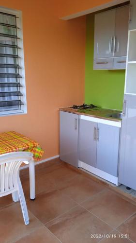 uma cozinha com armários brancos e uma parede verde em Entre Mer et Montagne em Goyave