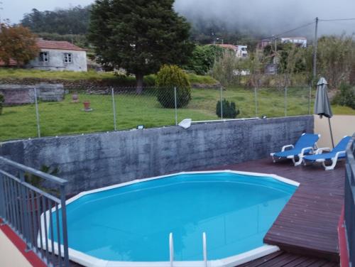 a swimming pool with a retaining wall and a fence at Casa do terno com piscina in Arco da Calheta