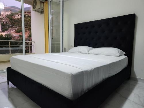 a large bed in a bedroom with a large window at Black'n White Apartment in Vlorë