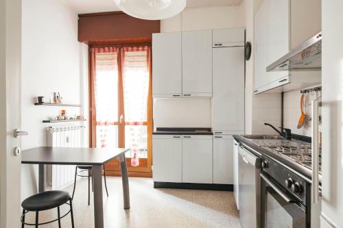 une cuisine avec des placards blancs et une table avec un tabouret dans l'établissement While apartment underground and bus station a/c, à Milan