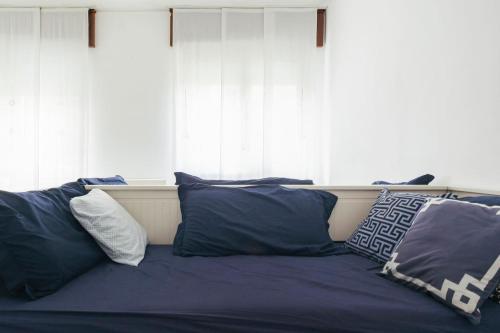 - un lit avec des oreillers bleus devant une fenêtre dans l'établissement While apartment underground and bus station a/c, à Milan