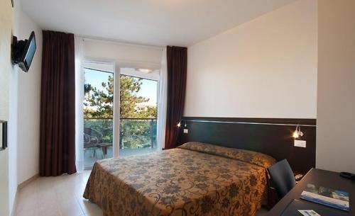 a hotel room with a bed and a large window at Hotel Bellevue in Lignano Sabbiadoro