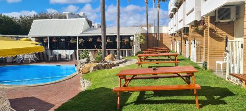 a row of picnic tables next to a pool at Indian Ocean Hotel in Perth