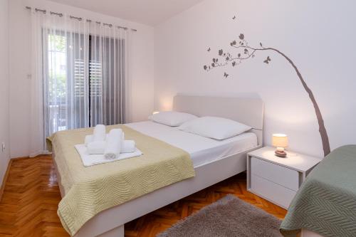 a white bedroom with a bed with two towels on it at Apartment Crikvenica 5494c in Crikvenica