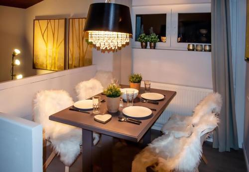 a dining room with a table with white fur chairs at Eifel Cottage Biersdorf am See in Biersdorf