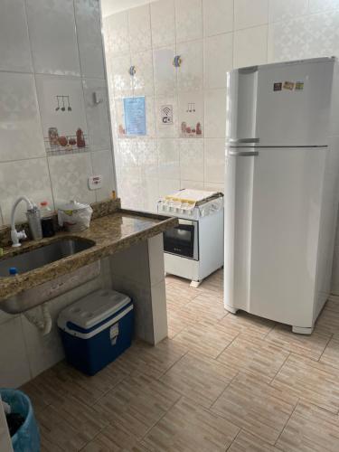 a kitchen with a white refrigerator and a sink at Condomínio Canto das Orquídeas VI in Porto Seguro
