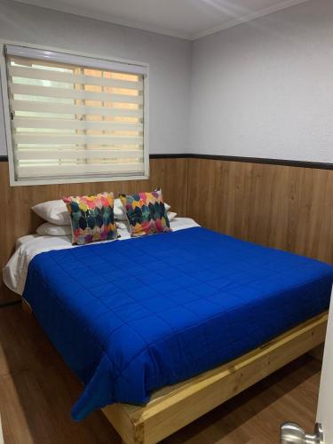 a bedroom with a blue bed with a window at La Quebrada de Pinomar in El Quisco