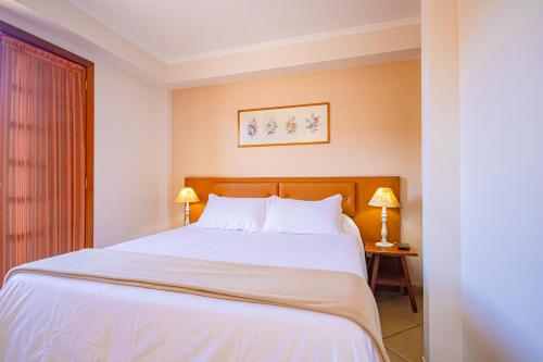 a bedroom with a large white bed with two lamps at Pousada Alemã in Santo Antônio do Pinhal