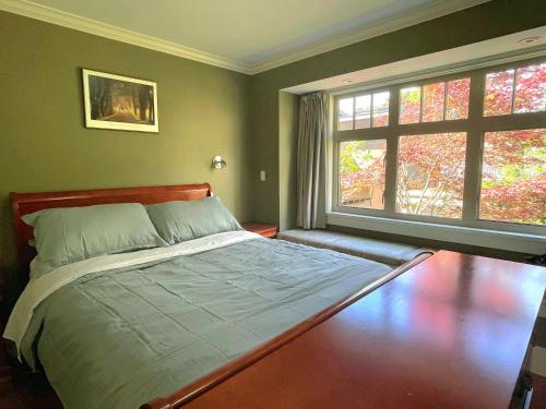 a bedroom with a bed and two windows at Elegant, Sunny Modern Home with Skylights - Kitsilano, Vancouver in Vancouver